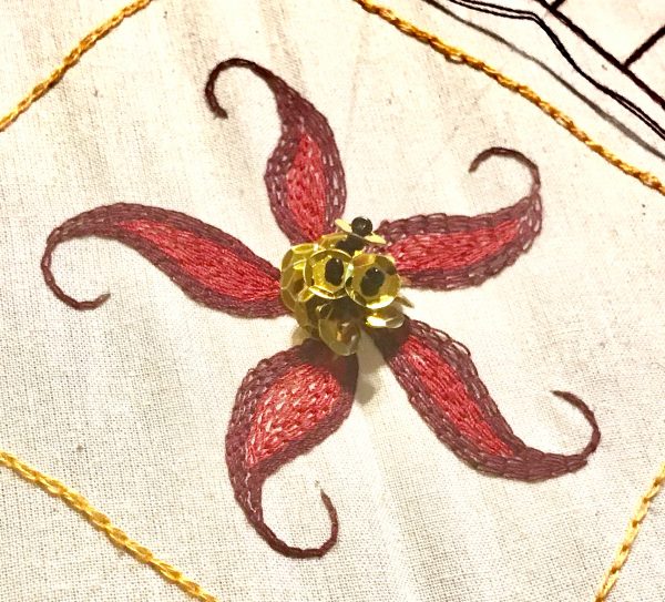 Five-point embroidered flower with beaded center in red and gold by Nathan Perez for the tambour class he will be teaching at Tchad workroom sewing studio in Chicago in August